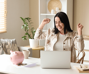 Woman celebrating while using a laptop after successfully managing her budget and finances from home.