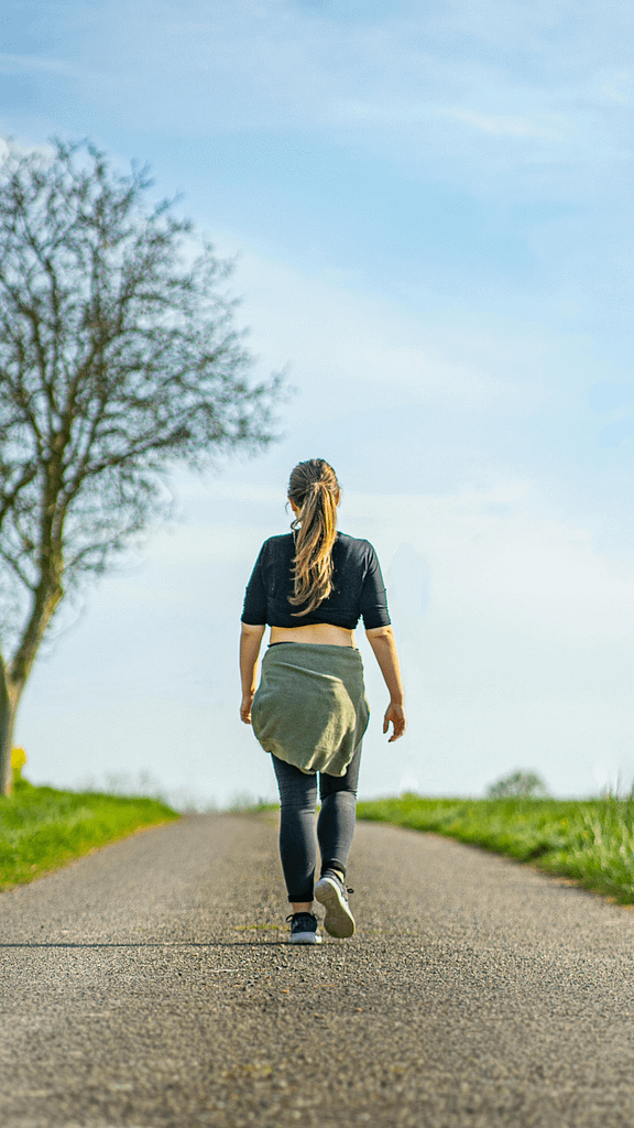 Woman walking alone on a quiet road representing personal growth, recovery and moving forward after gambling addiction.